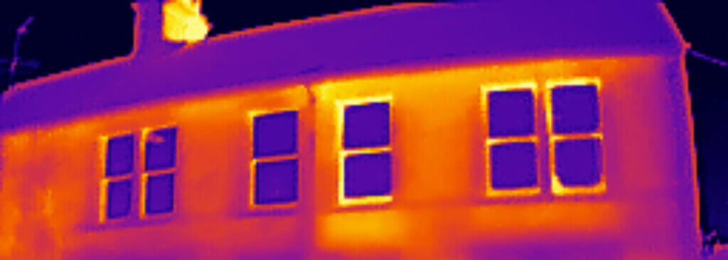 Thermal image of a house in Cambridge highlights heat distribution. Warmer areas are brighter, cooler ones darker. The roof, walls, and windows show varying thermal signatures, hinting at potential benefits from sash windows repair for improved insulation efficiency.