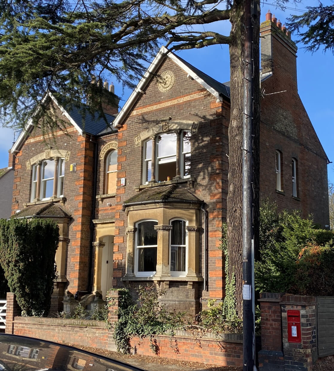 A brick house with a car parked in front of it, featuring beautifully restored sash windows.