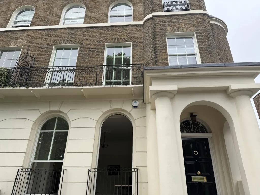 Arched sash windows and a curved brick bay above the stucco entrance of a Grade 2 listed house in St John's Wood