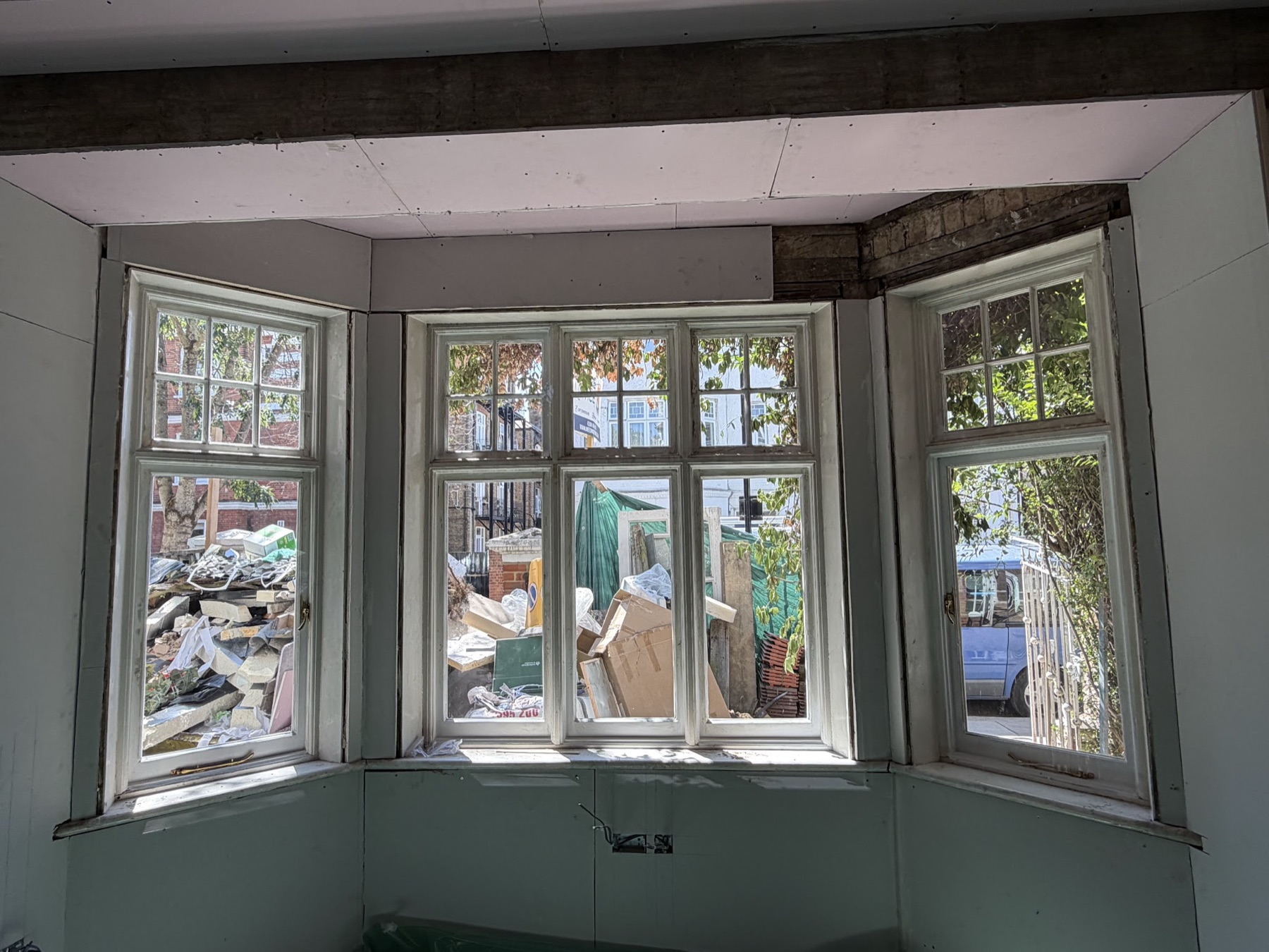 The casement bay seen from inside during the works, three lights with six-pane top lights, the room stripped back for renovation