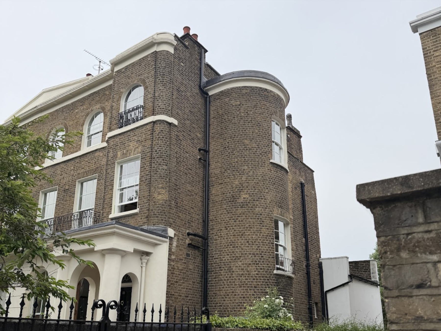 Side elevation showing the curved brick bay with curved sash windows on two floors beside the arched windows of the main elevation