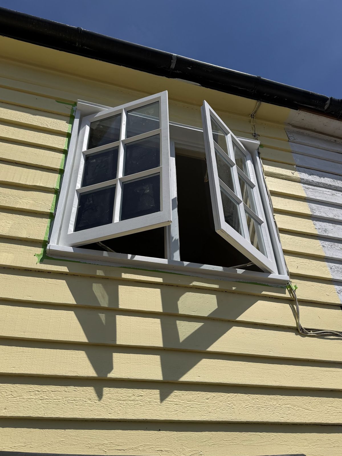 Pair of timber casement windows open during restoration on a weatherboarded house
